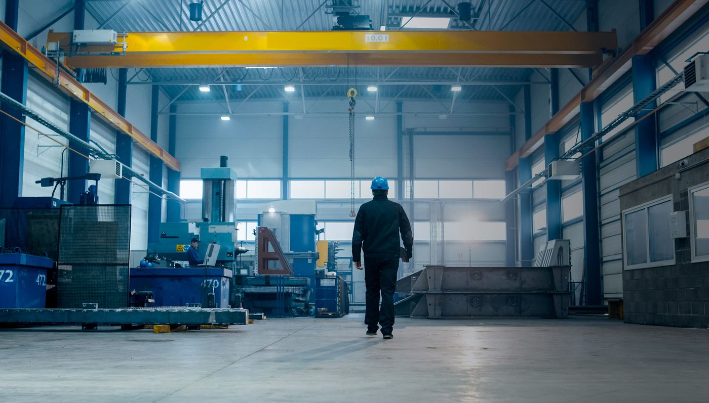 Técnico con casco recorriendo una nave industrial